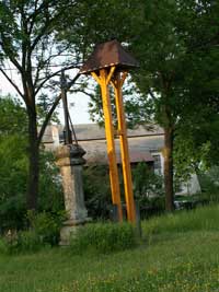 litinový křížek s kamenným podstavcem, v pozadí zvonička v Boříkovech