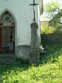 litinový křížek s kamenným podstavcem před kaplí v Buršicích